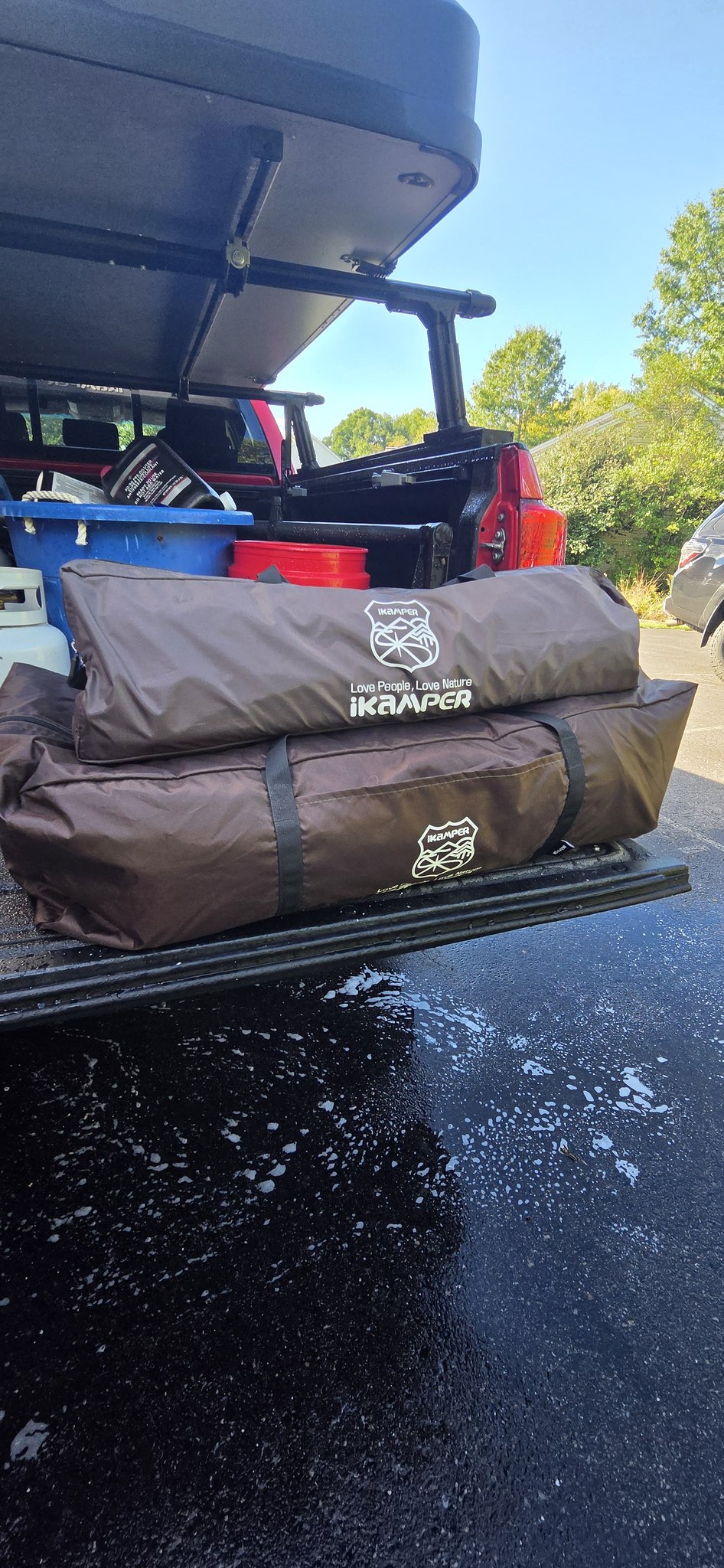 Two iKamper accessory storage bags holding the annex and canopy, set on the open tailgate — photo 7