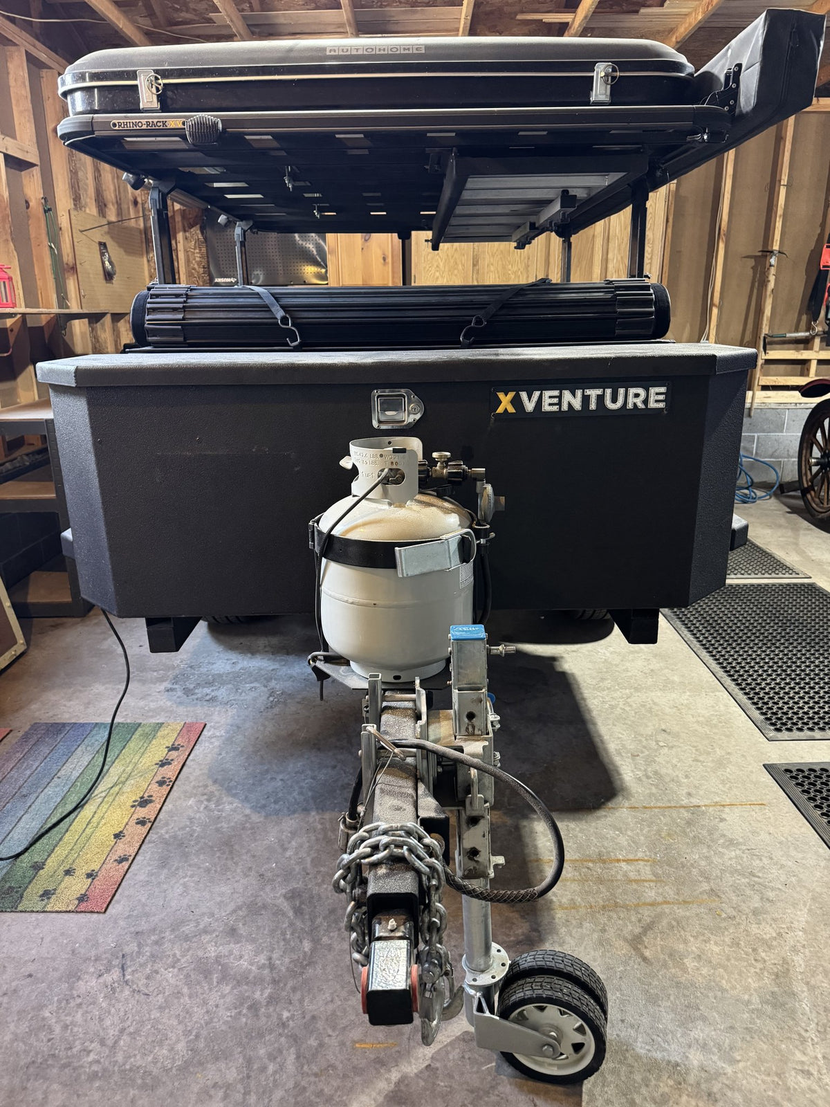 Front of the trailer showing the lockable XVENTURE front storage box, front-mounted propane tank, coupler and swing-up jack wheel — photo 16