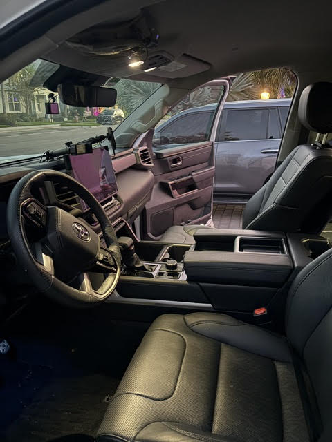 Driver's side of the cab showing the leather steering wheel, instrument cluster, centre console shifter and black leather front seats — photo 19