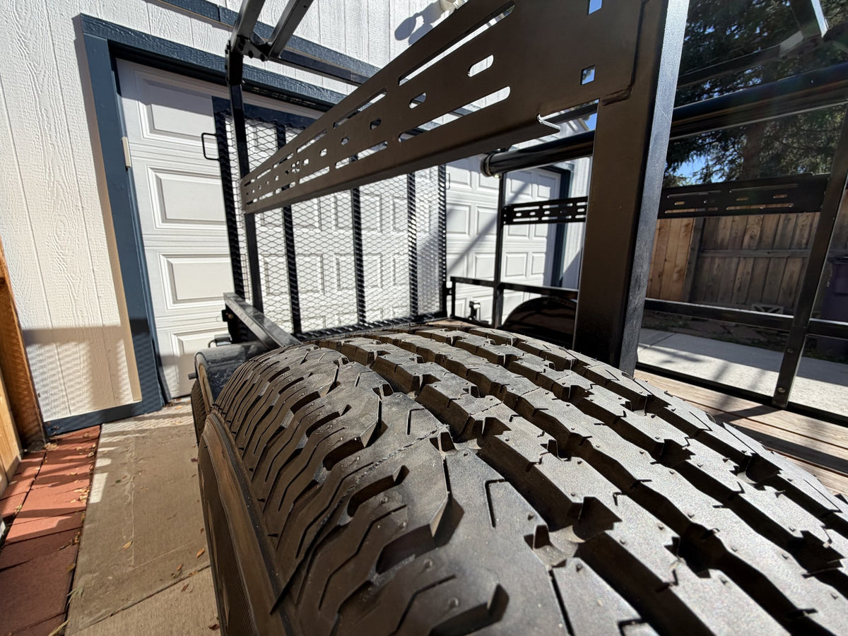 Close view of the mounted spare tire tread with the slotted rack crossbar and mesh gate behind it — photo 11
