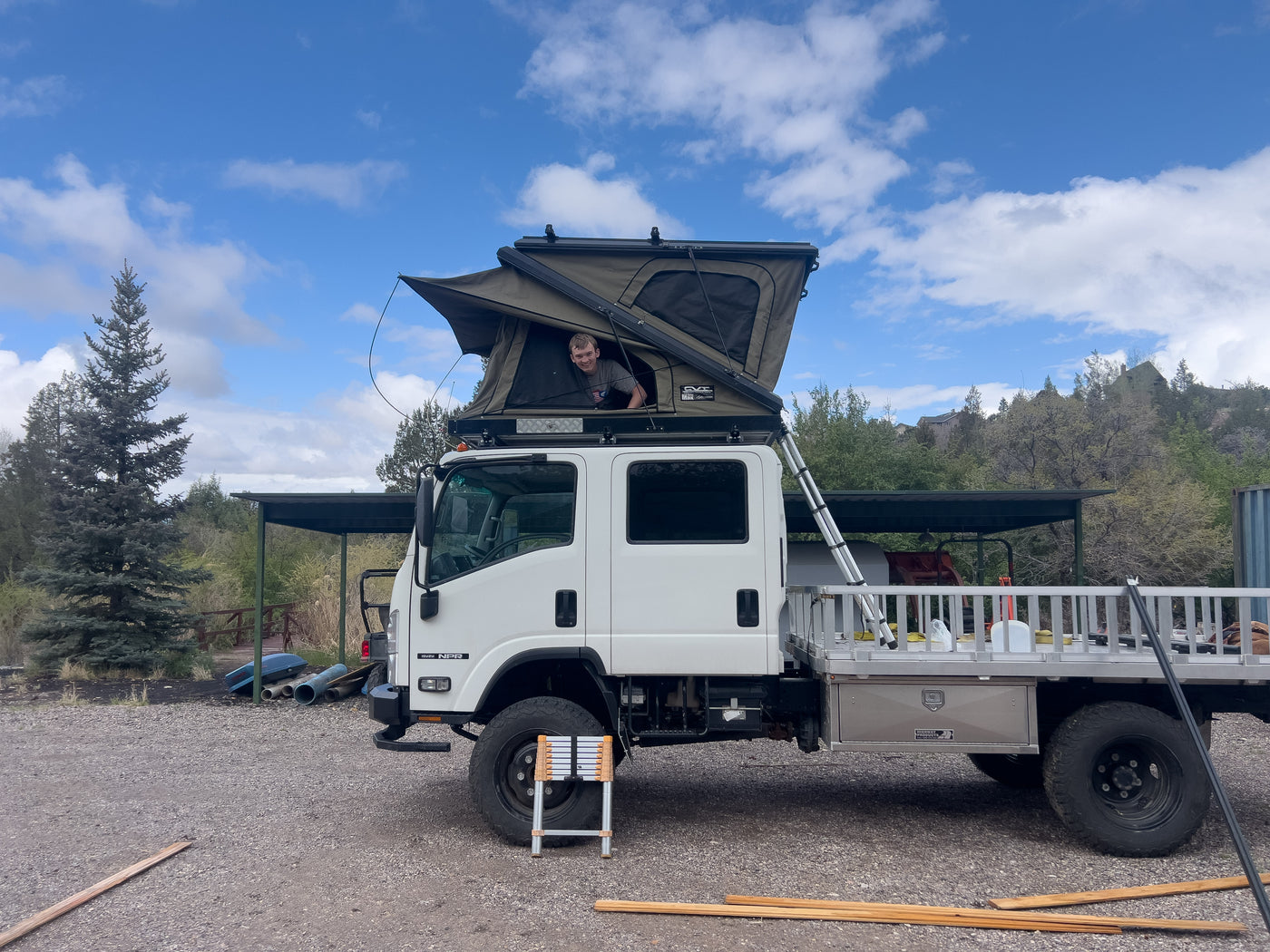 Isuzu NPR expedition rig at camp with rooftop tent open — photo 3