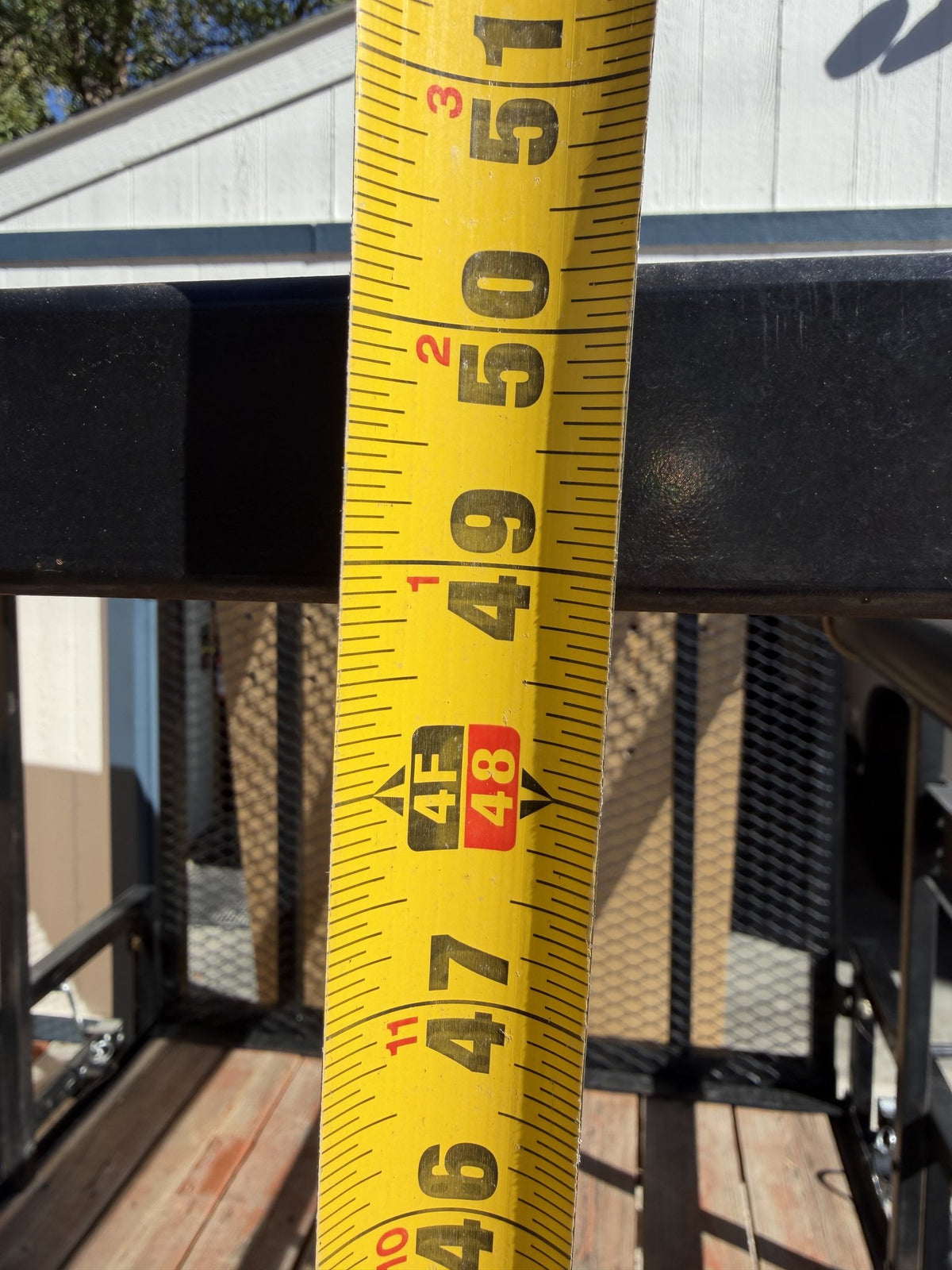 Tape measure held across a rack upright reading just under 48 inches, a dimension reference for the overhead rack opening — photo 13