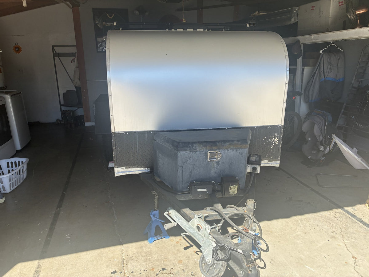 Front view of the teardrop trailer with the A-frame tongue, coupler, jack stand, battery box and diamond-plate front skirt — photo 3