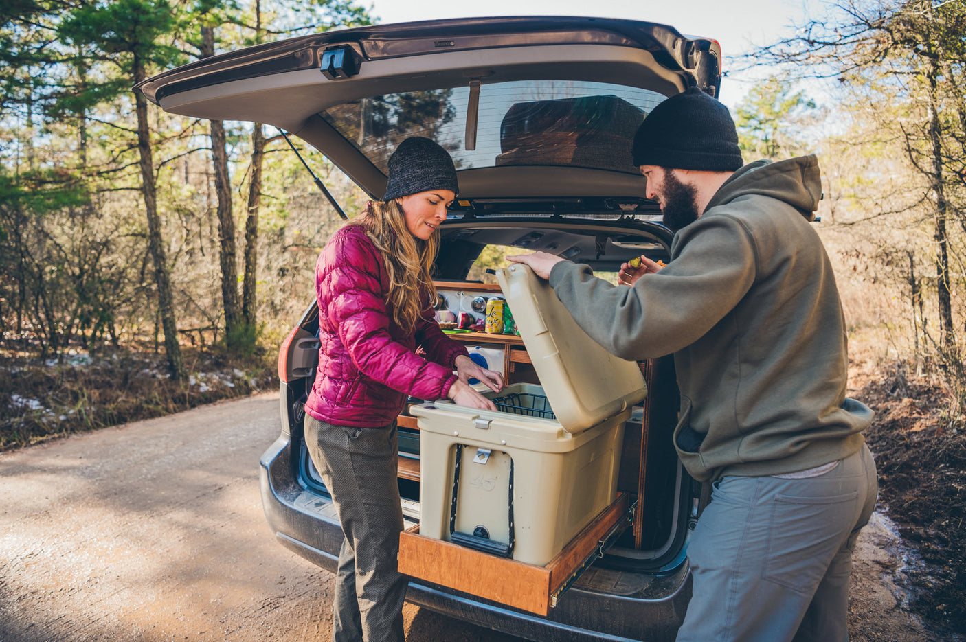 ideal for RV rental road trips.|Couple preps their custom SUV's cooler and gear for a car camping adventure. Experience similar road trip freedom with an RV rental!|Compact RV rental kitchen setup with a magnetic spice rack featuring dill