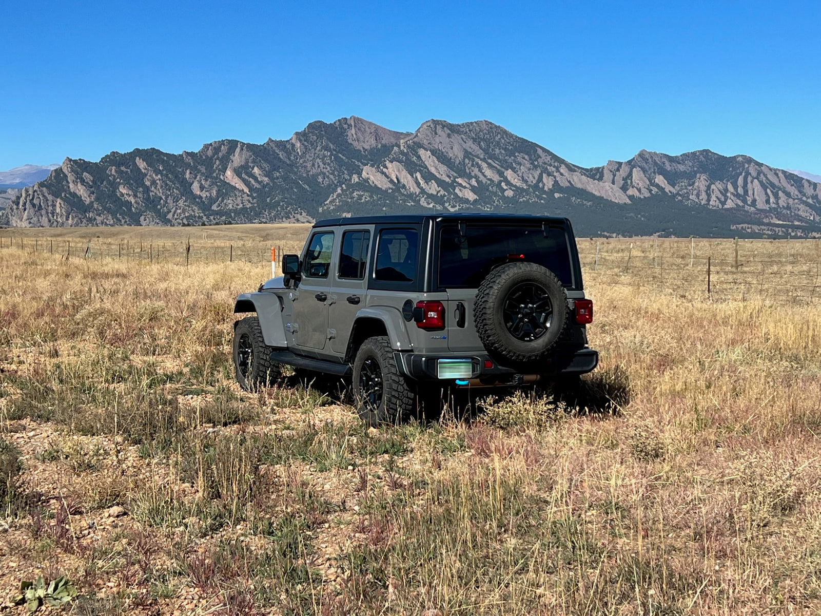 Gray Jeep Wrangler in a field with mountains. Great for exploring where RV rentals can't go.