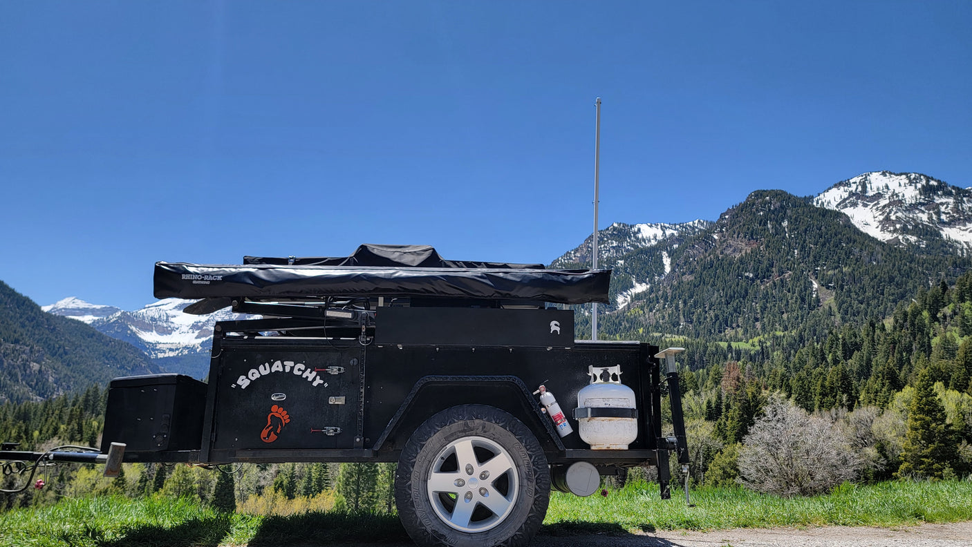 "Squatchy" black overland **rv rental** with awning & propane, ready for mountain camping adventure.