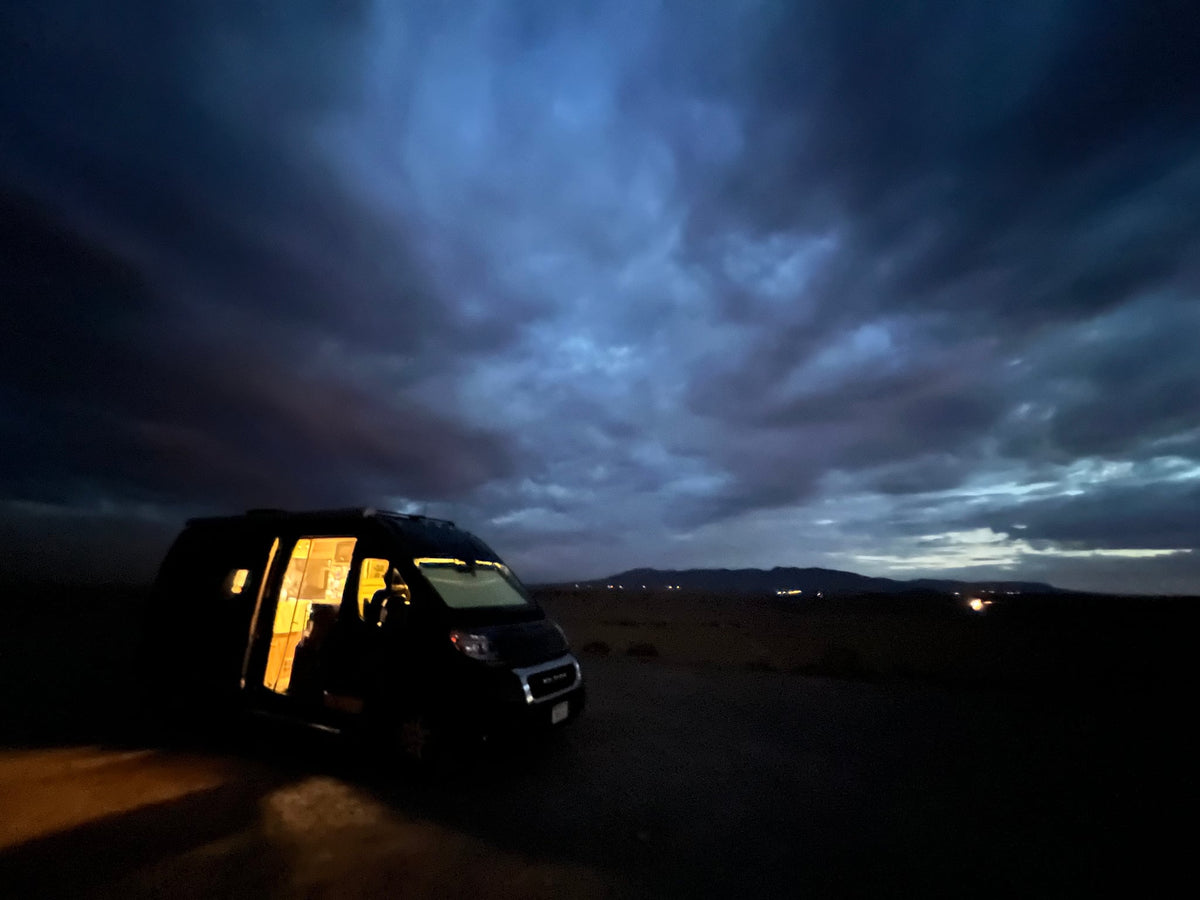 is ready for adventure! Parked beside a unique stone mansion.|An RV rental basks in a vibrant desert sunset — photo 3