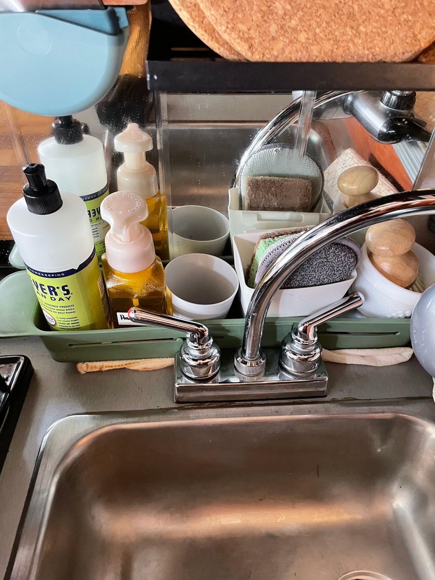 RV rental kitchen sink, tidy with dish soap, sponges, and supplies in a caddy behind the modern chrome faucet.