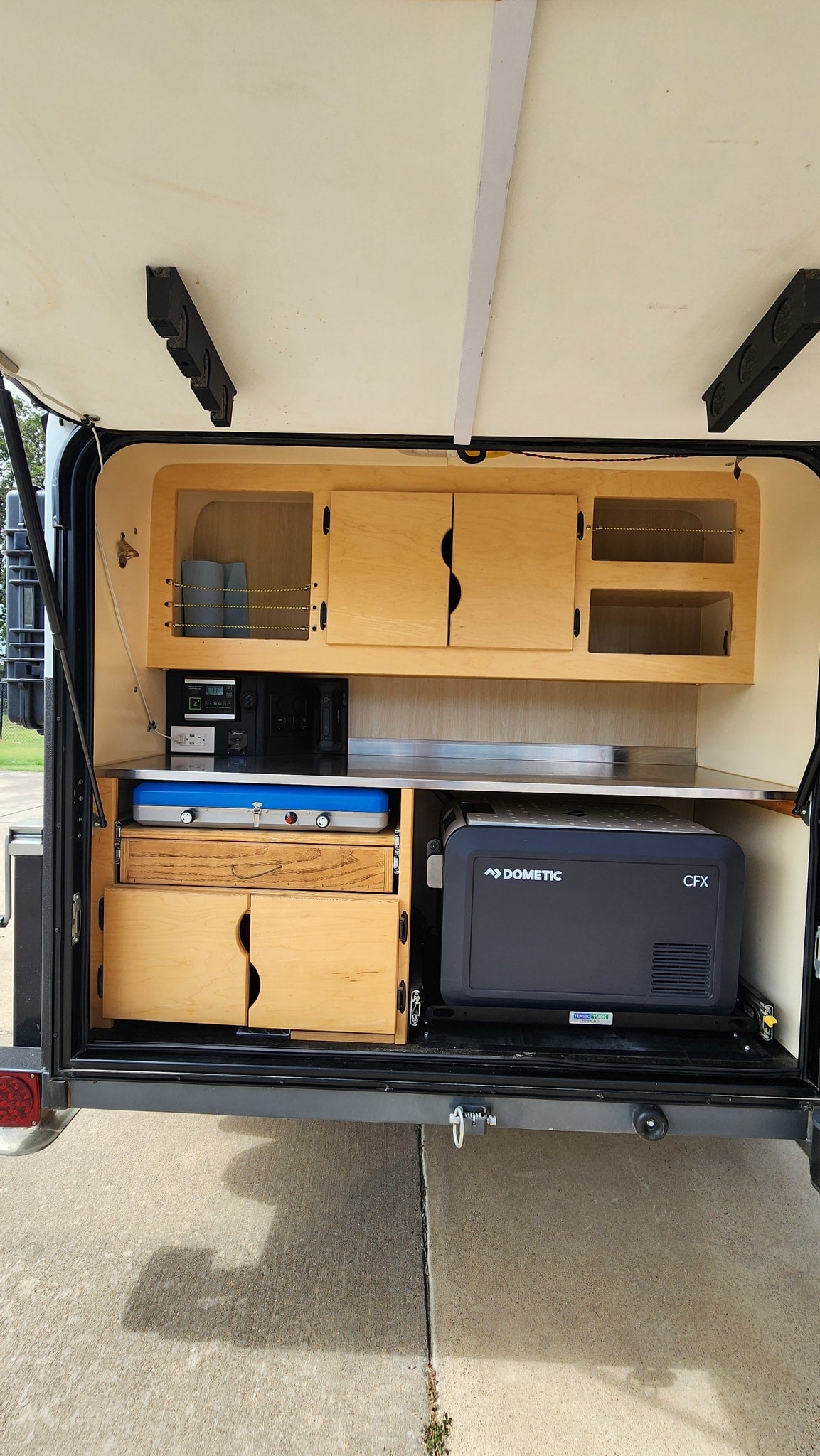 RV rental teardrop trailer's rear galley features a Dometic fridge, portable stove, Zamp power system, and wood cabinets. Ideal for camping.