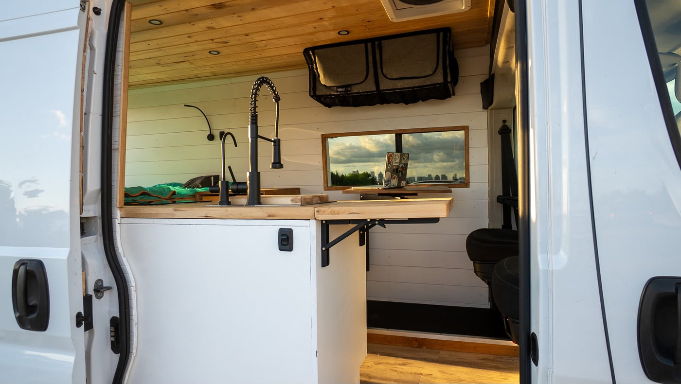 This RV rental features a modern kitchen with a black faucet, wood counters, and a scenic window view of a city skyline. — photo 7