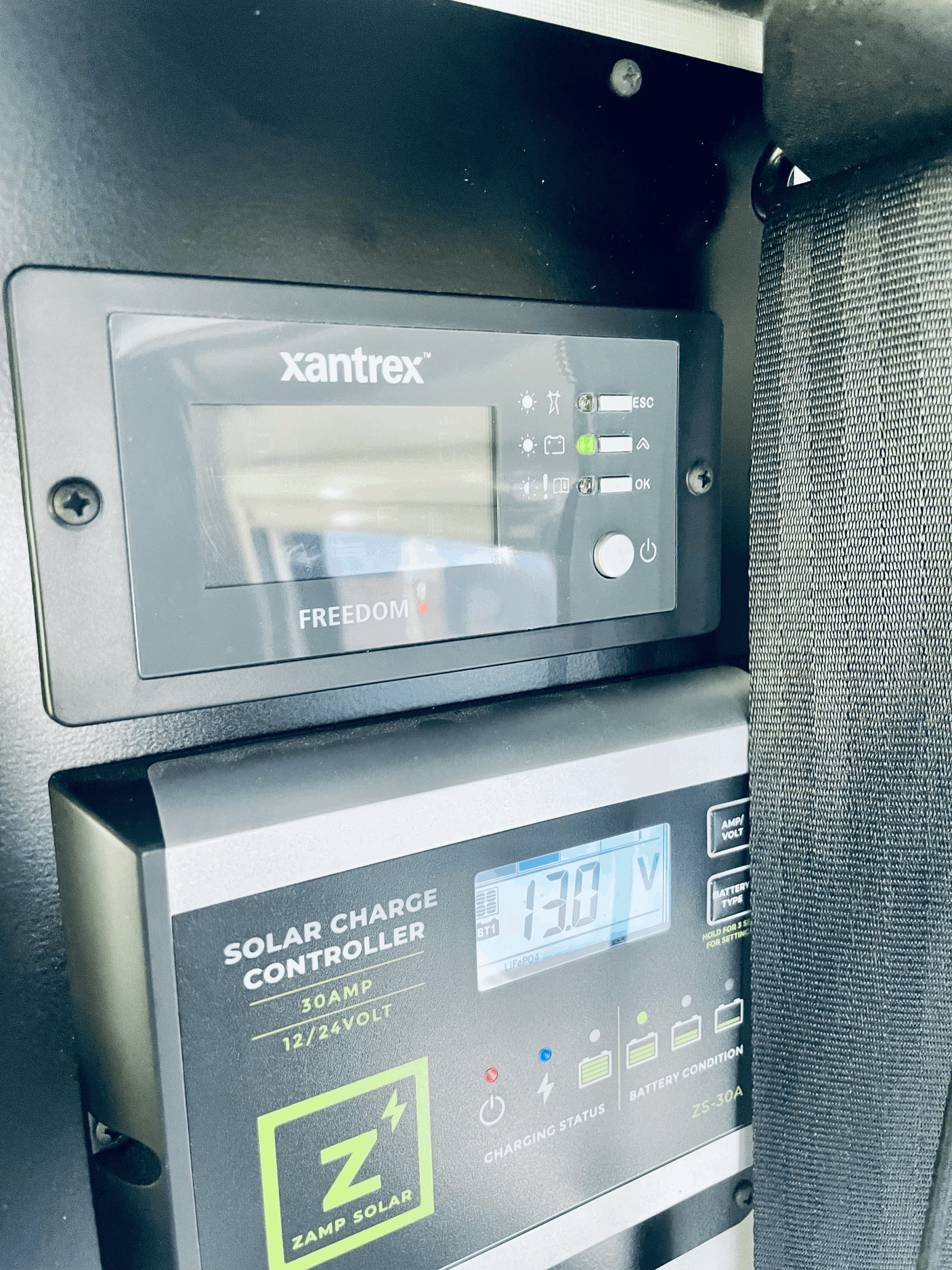 RV rental: A Zamp Solar charge controller displays 13.0V below a Xantrex power monitor, managing battery charging.