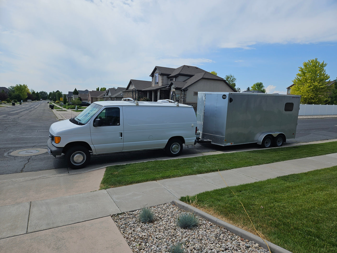White cargo van and utility trailer parked. Versatile setup for hauling, a practical alternative to an RV rental.