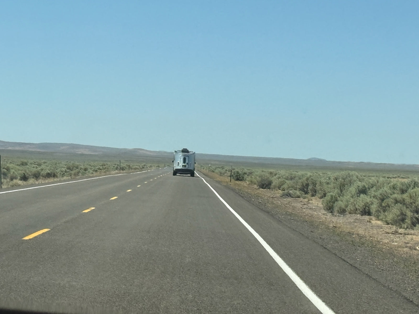 and drain.|RV rental overhead view: A white AC unit with air vents and Coleman Mach controls for heating and cooling comfort.|Airstream Basecamp RV rental interior with modular green and patterned cushions forming a bed