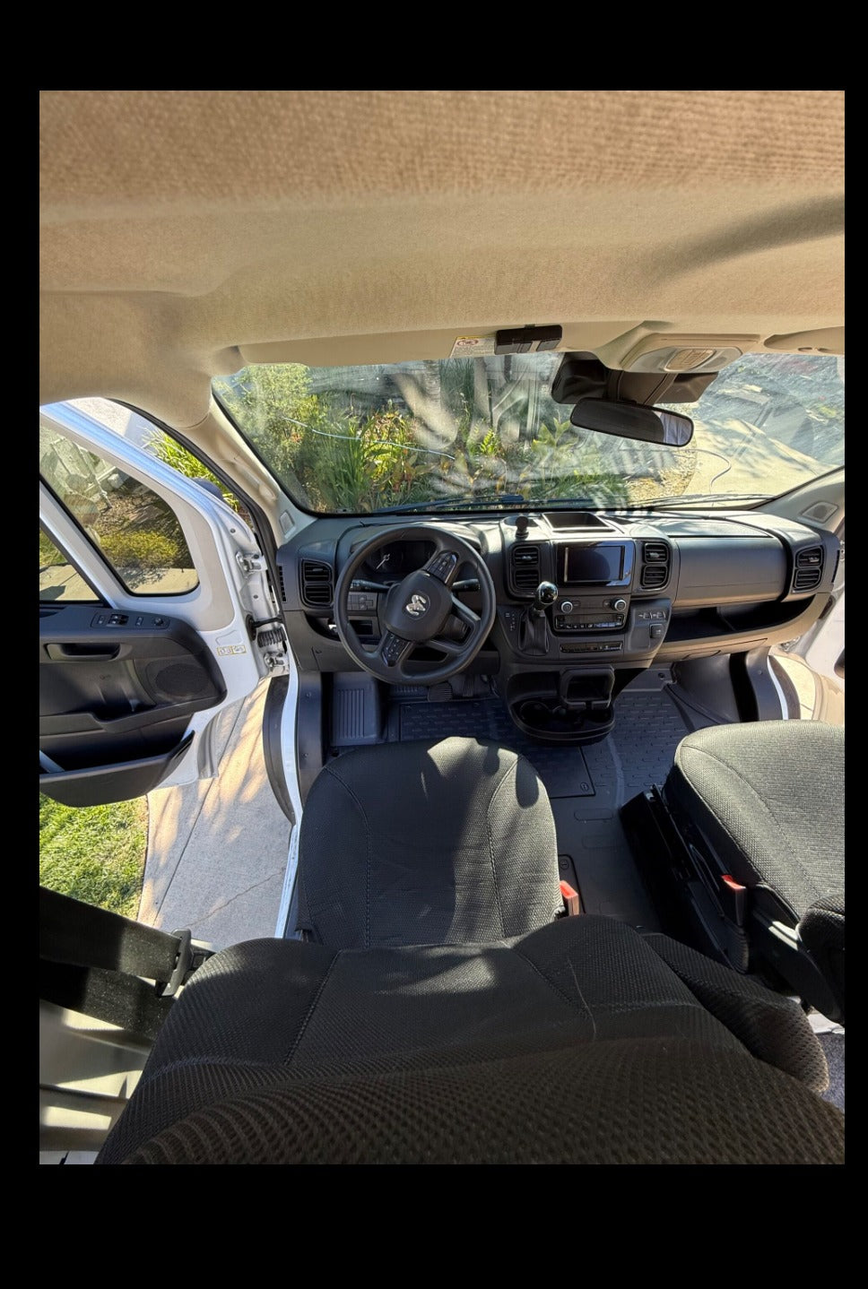 RV rental van interior from above: dashboard, steering wheel, and front seats are clearly visible, with an open door.