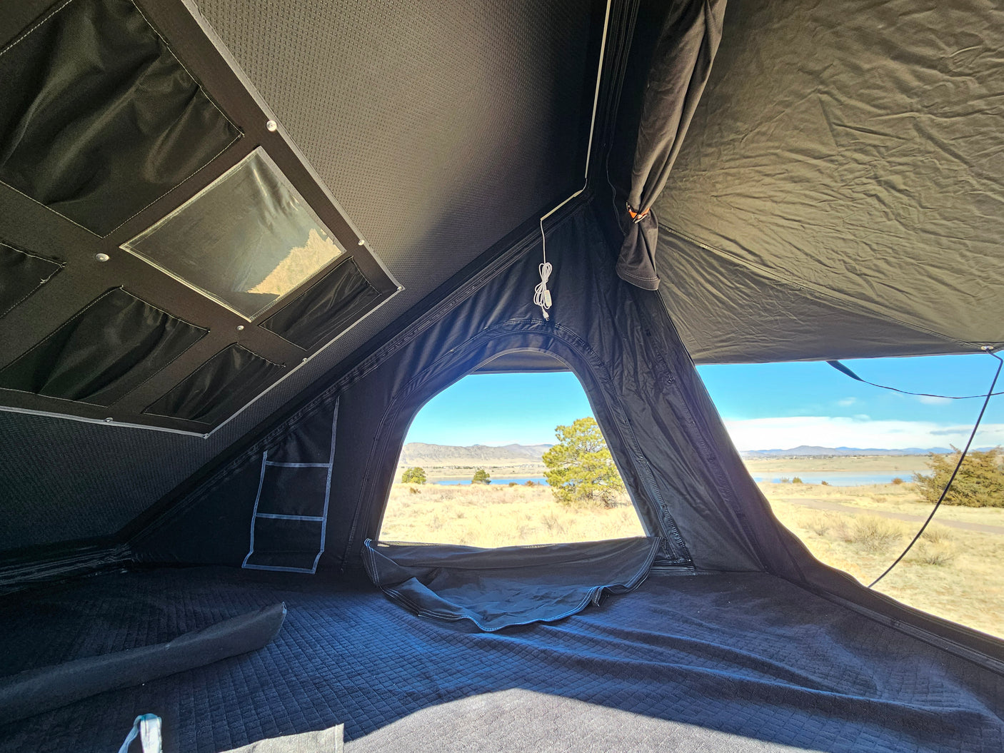 Experience camping comfort! This RV rental features a rooftop tent with a comfy mattress and beautiful lakeside views.