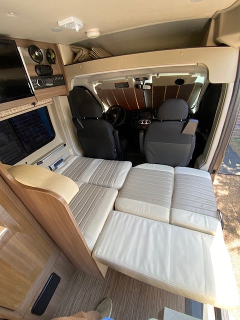 RV rental interior: spacious camper van with convertible bed and forward cockpit view. Ready for your adventure.