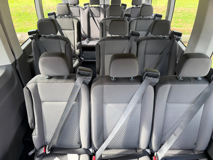 Interior of an RV rental van featuring multiple rows of grey passenger seats with safety belts, ideal for group trips.