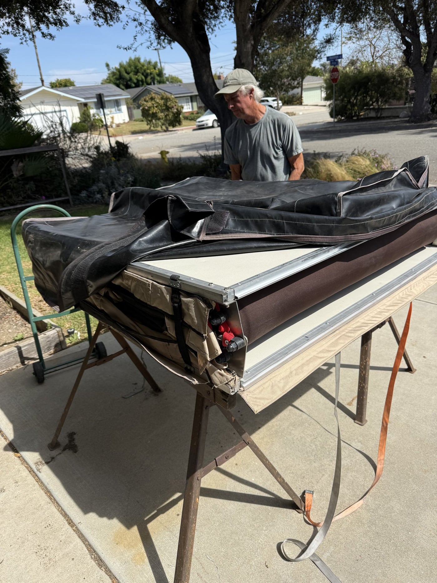 Folded tent with the black travel cover partly pulled over it, showing base rails and the red mounting hardware in the channel — photo 12