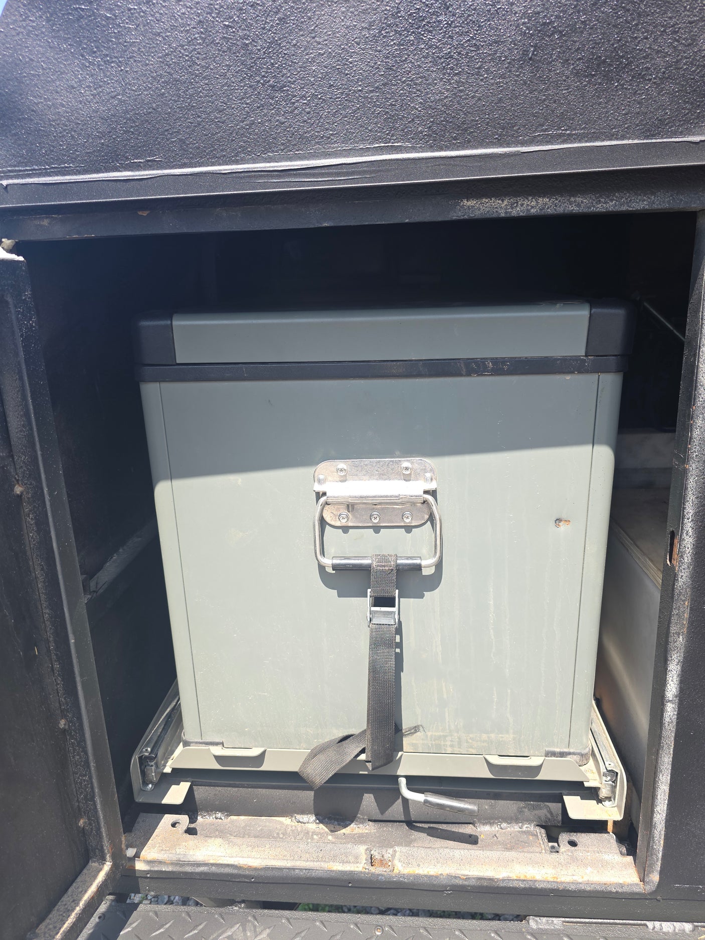 RV rental ready: A heavy-duty gray storage box on a pull-out slide system within a vehicle compartment, ideal for gear.
