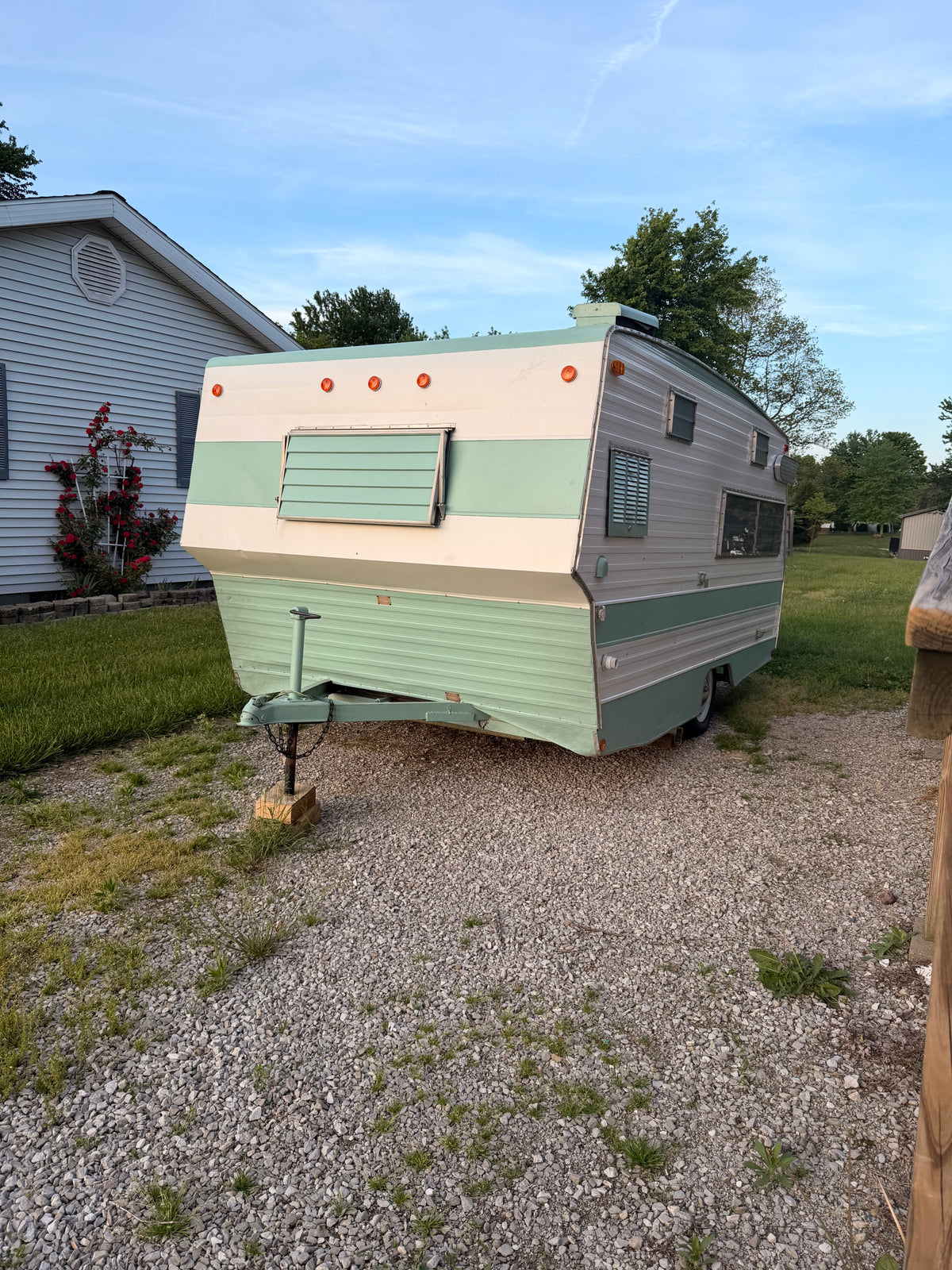 This vintage travel trailer RV rental, parked on gravel next to a home with roses, offers a nostalgic outdoor experience. — photo 8
