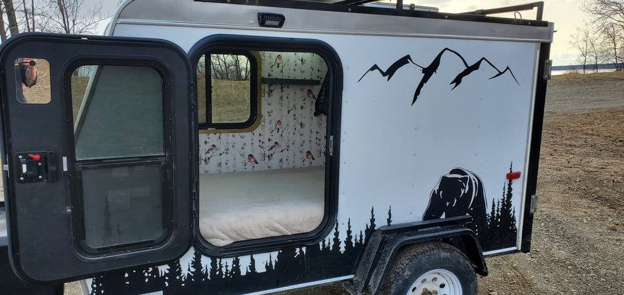 Cozy RV rental camper: custom bear and mountain exterior, warm interior with birch tree & bird wallpaper. Perfect for outdoor adventure.