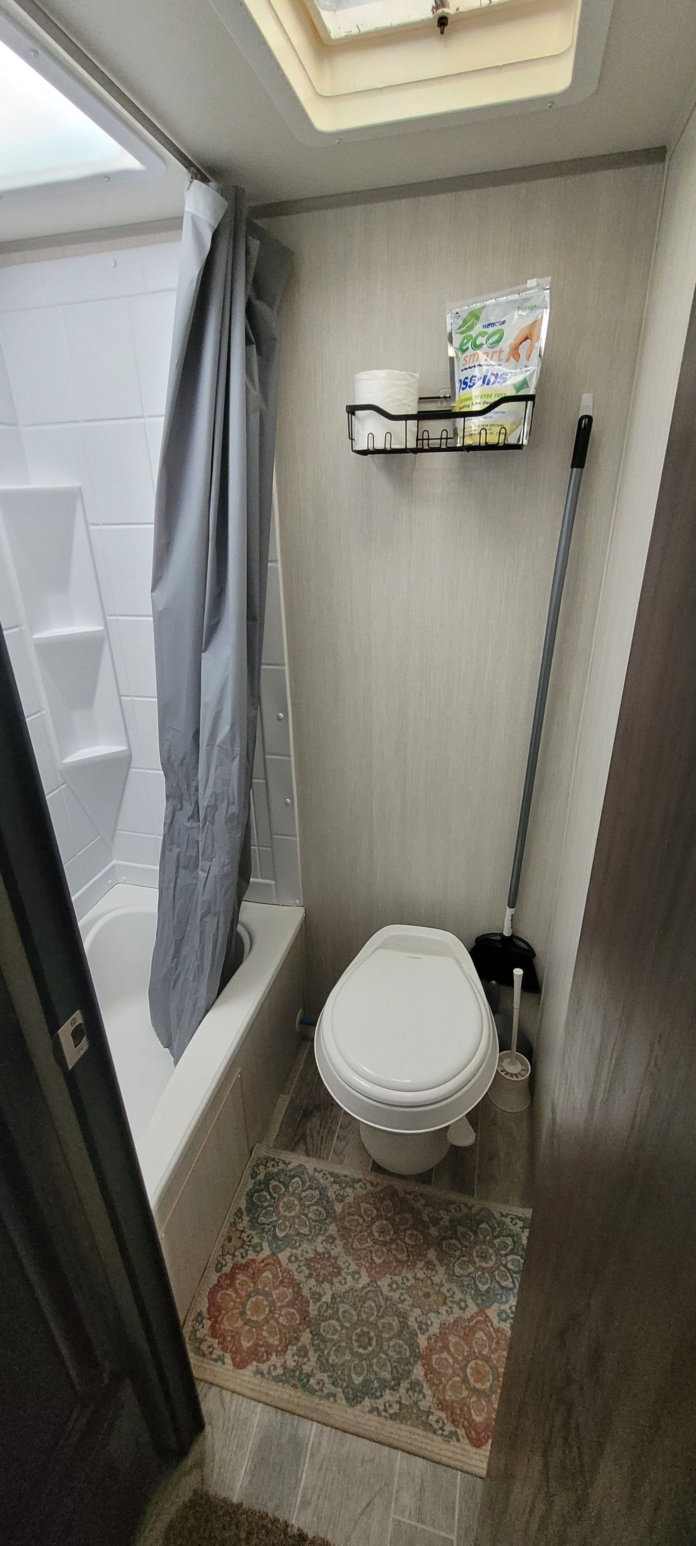 Inside an RV rental: a compact bathroom with a toilet, shower, cleaning supplies, and a small wall organizer.
