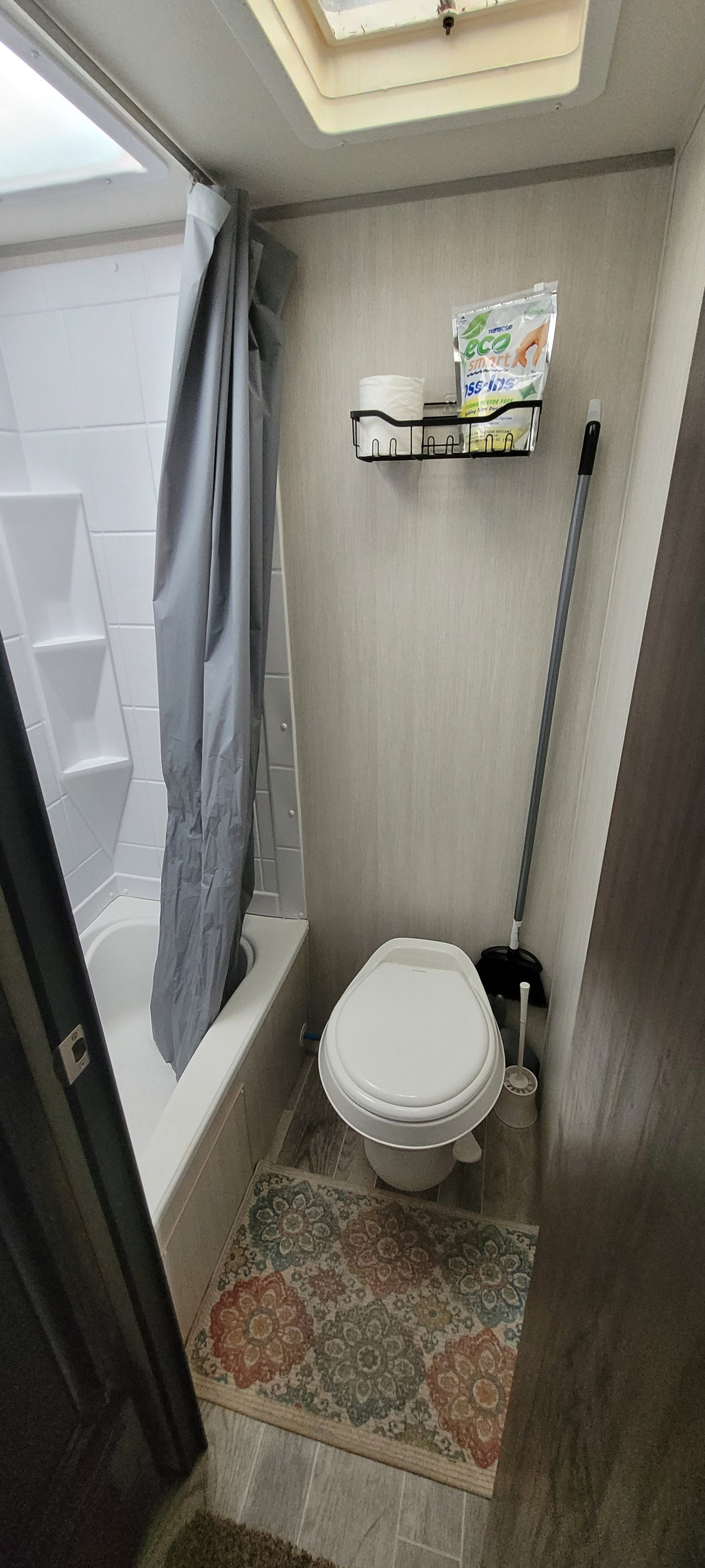 Inside an RV rental: a compact bathroom with a toilet, shower, cleaning supplies, and a small wall organizer.