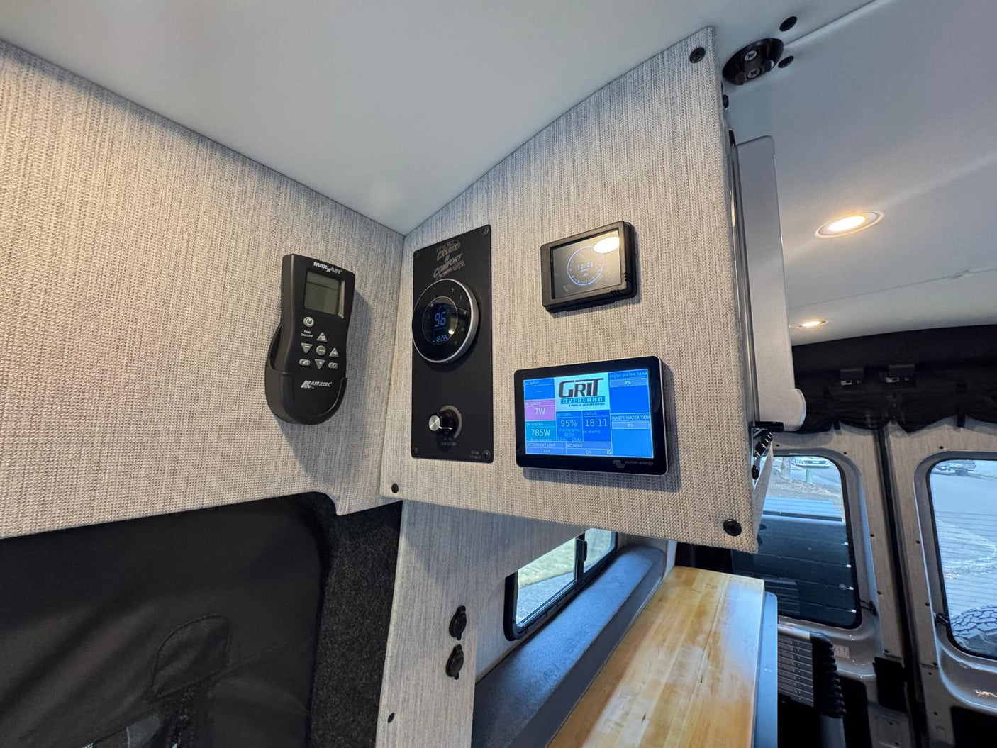 Modern **RV rental** interior showing mounted MaxxAir fan, climate control, and Grit Overland power/tank monitors.