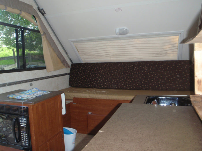 and beloved pets (dog & cat). Ready for your next adventure!|Cozy RV rental interior features a compact kitchen with microwave and sink
