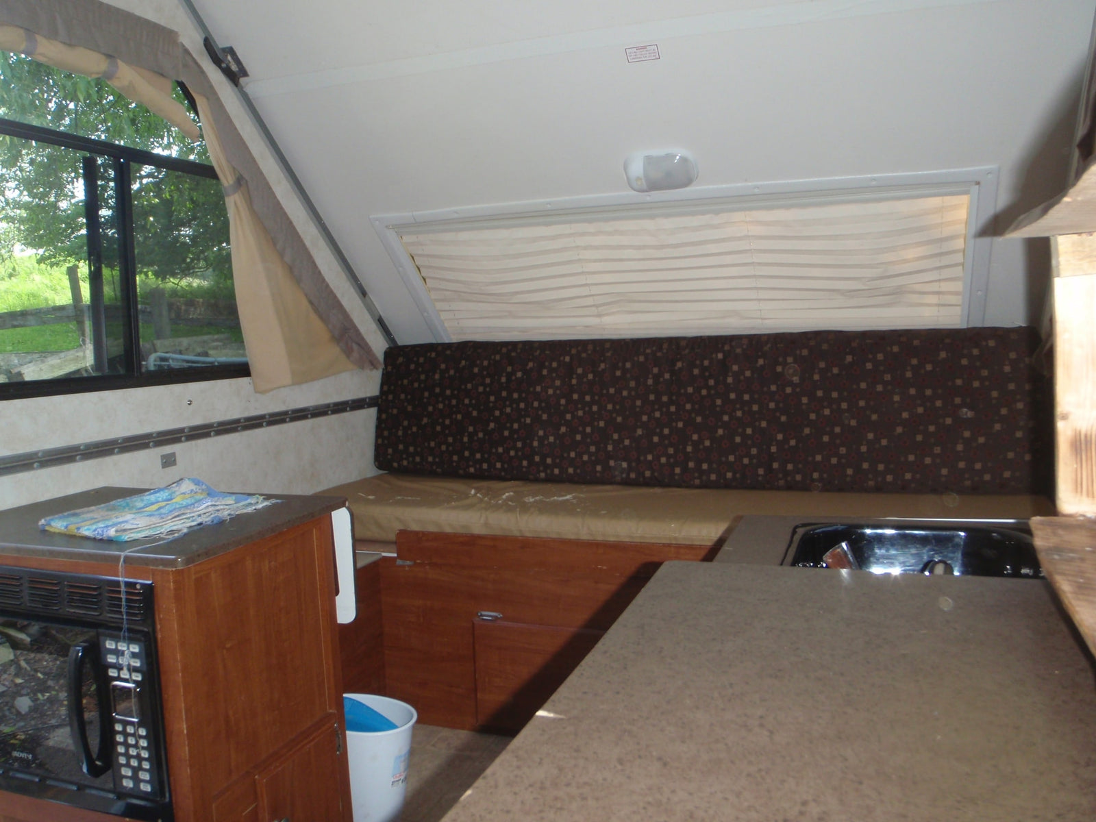 and beloved pets (dog & cat). Ready for your next adventure!|Cozy RV rental interior features a compact kitchen with microwave and sink