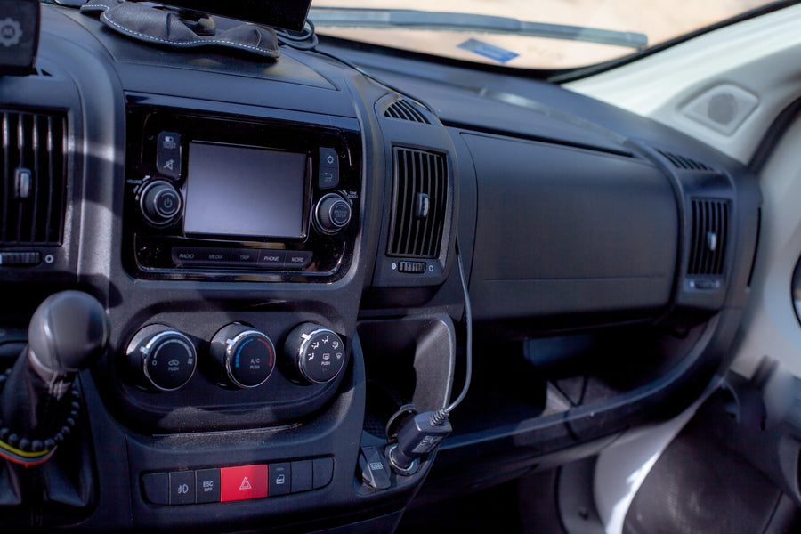 RV rental dashboard showcasing the infotainment screen, climate control dials, gear stick, and USB charging.