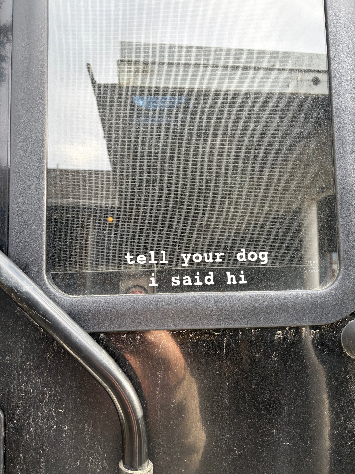 A dusty RV rental window with a screen displays 'tell your dog i said hi', hinting at dog-friendly travel.