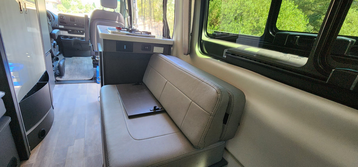 RV rental interior: Light-toned bench seat, compact kitchen counter with sink/stove, and driver's area visible, ready for adventure. — photo 3