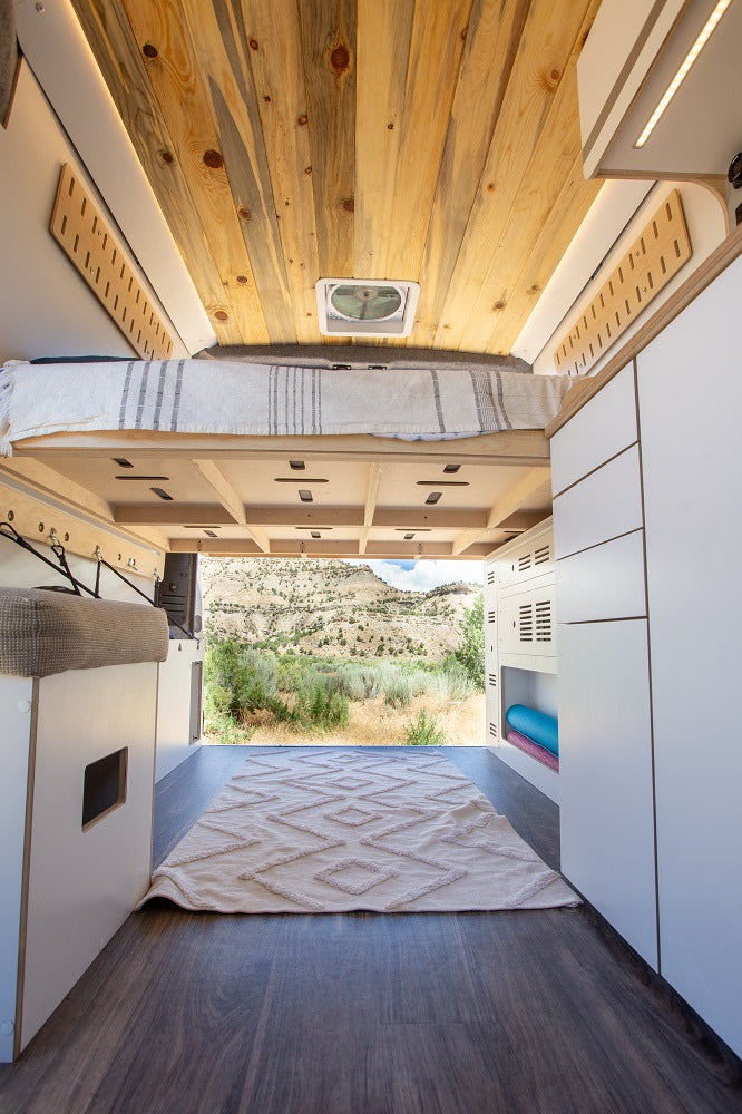 Experience comfort in this rv rental. A cozy bed, wood ceiling, and ample storage lead to scenic mountain views.