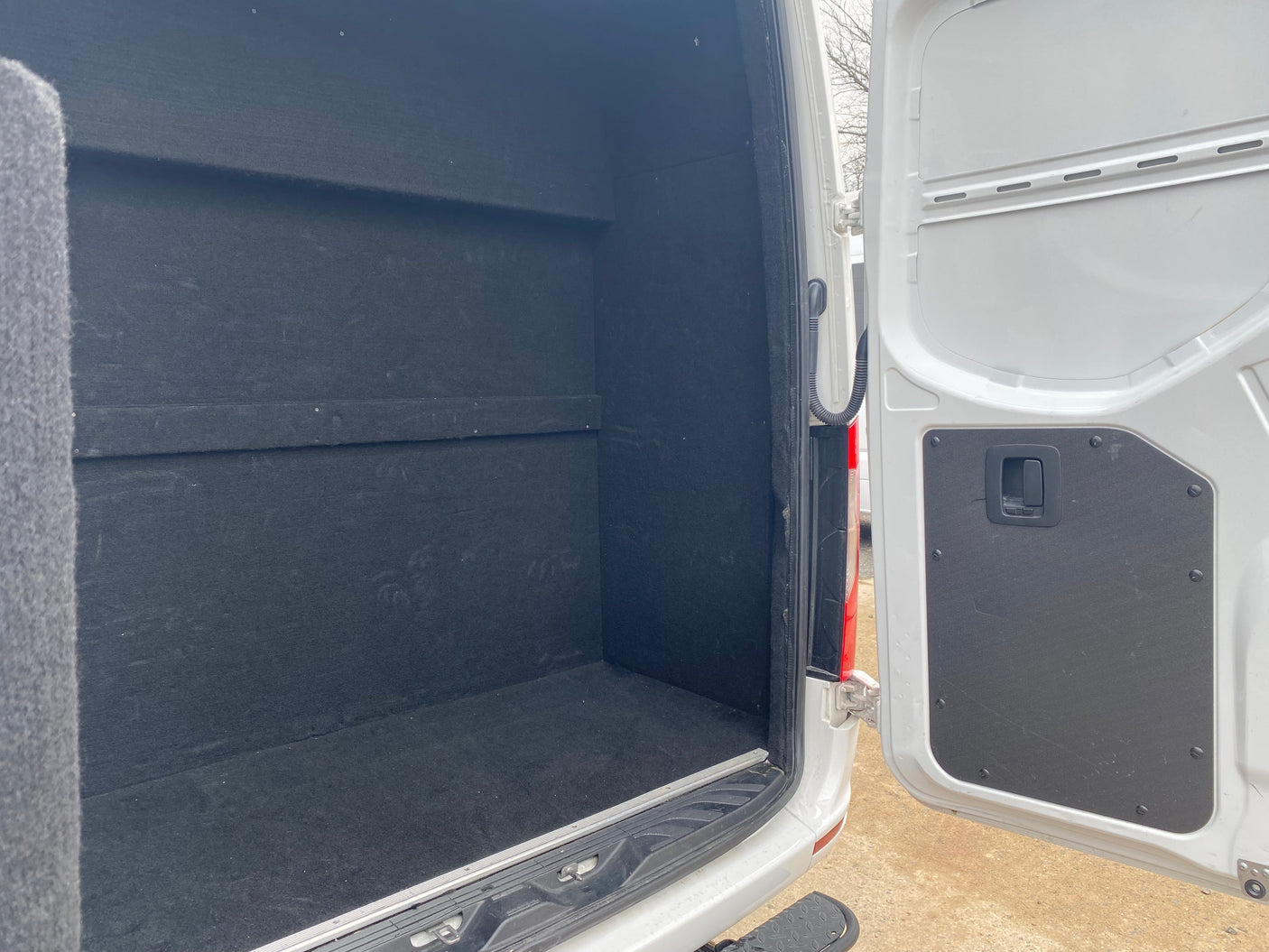 Spacious, black-lined van interior, ready for RV rental. Ample cargo space for your next campervan adventure.
