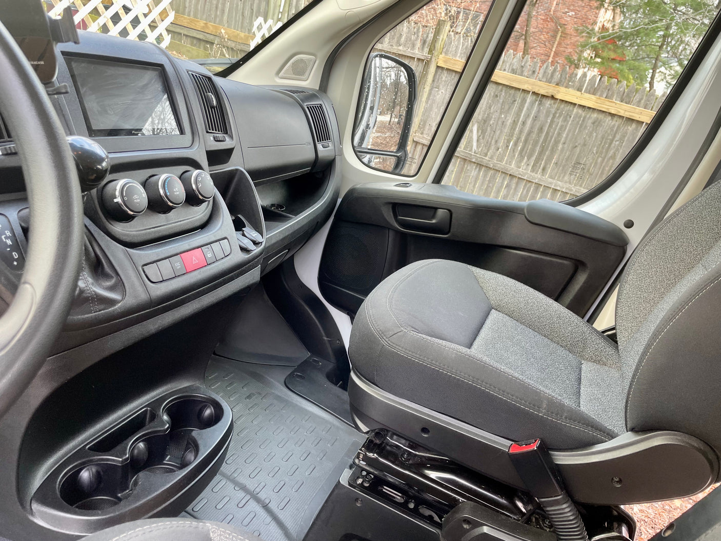 RV rental van's passenger interior: dashboard with Pioneer screen, climate controls, cupholders, and fabric seat.