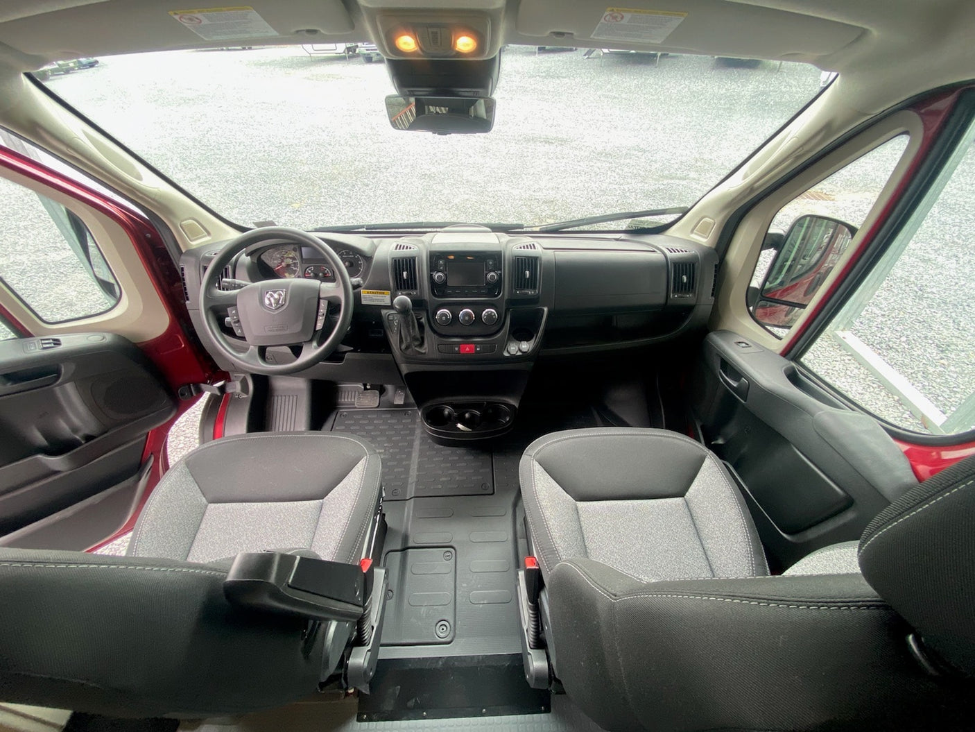 View from inside an RV rental van, featuring its spacious front cabin, dashboard, and comfortable driver and passenger seats.