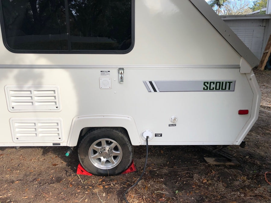 is seen deployed in a yard with trees.|White A-Liner "Scout" A-frame pop-up camping trailer