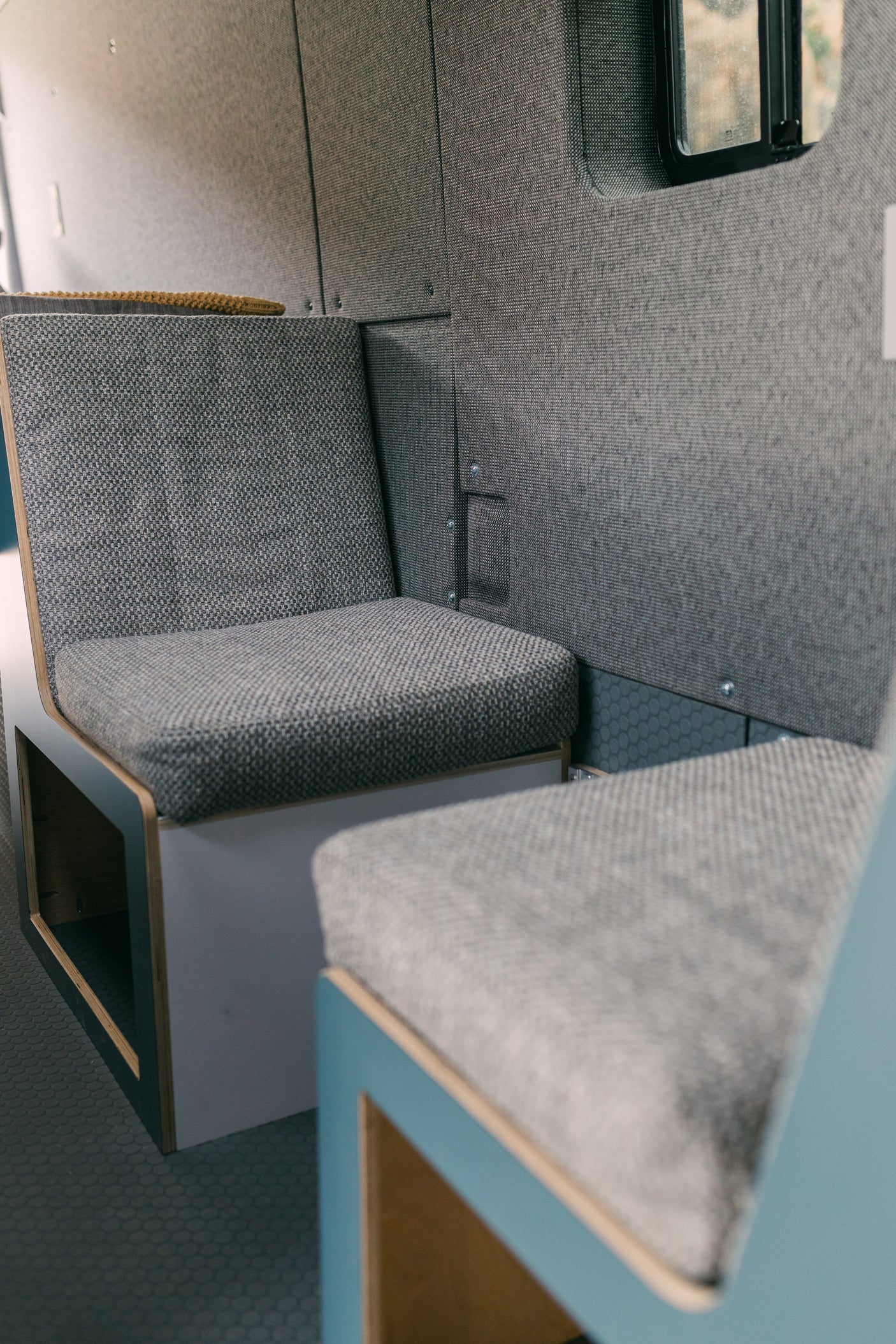 Modern grey upholstered seating and paneling in a clean RV rental interior, ready for comfortable camper van travel.