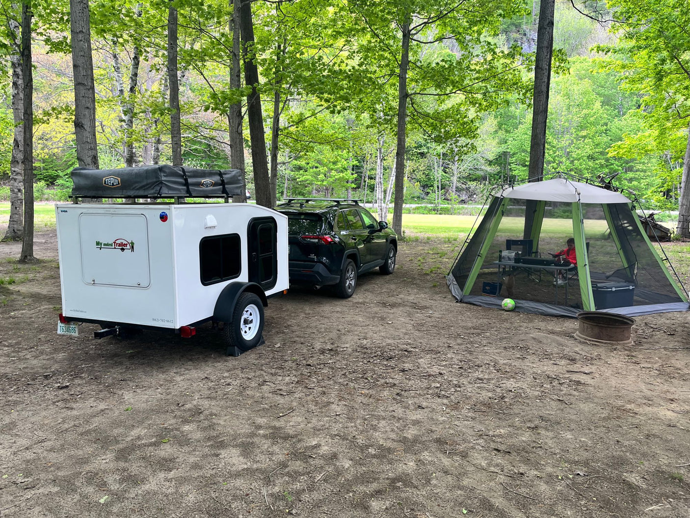 next to a red pickup truck.|Experience nature with this white compact travel trailer. Perfect for an RV rental