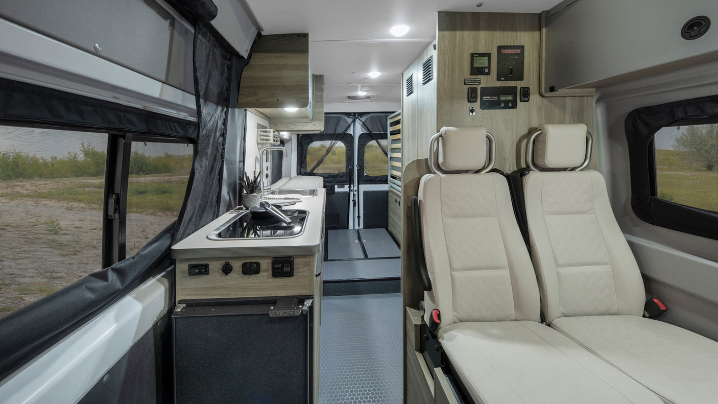Spacious RV rental interior featuring a modern kitchen, comfortable seating, and controls for mobile living.