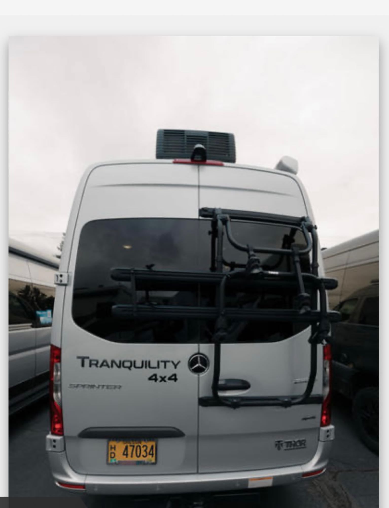 White Thor Tranquility 4x4 Mercedes-Benz Sprinter rv rental showing its rear, with a bike rack and rooftop AC unit.