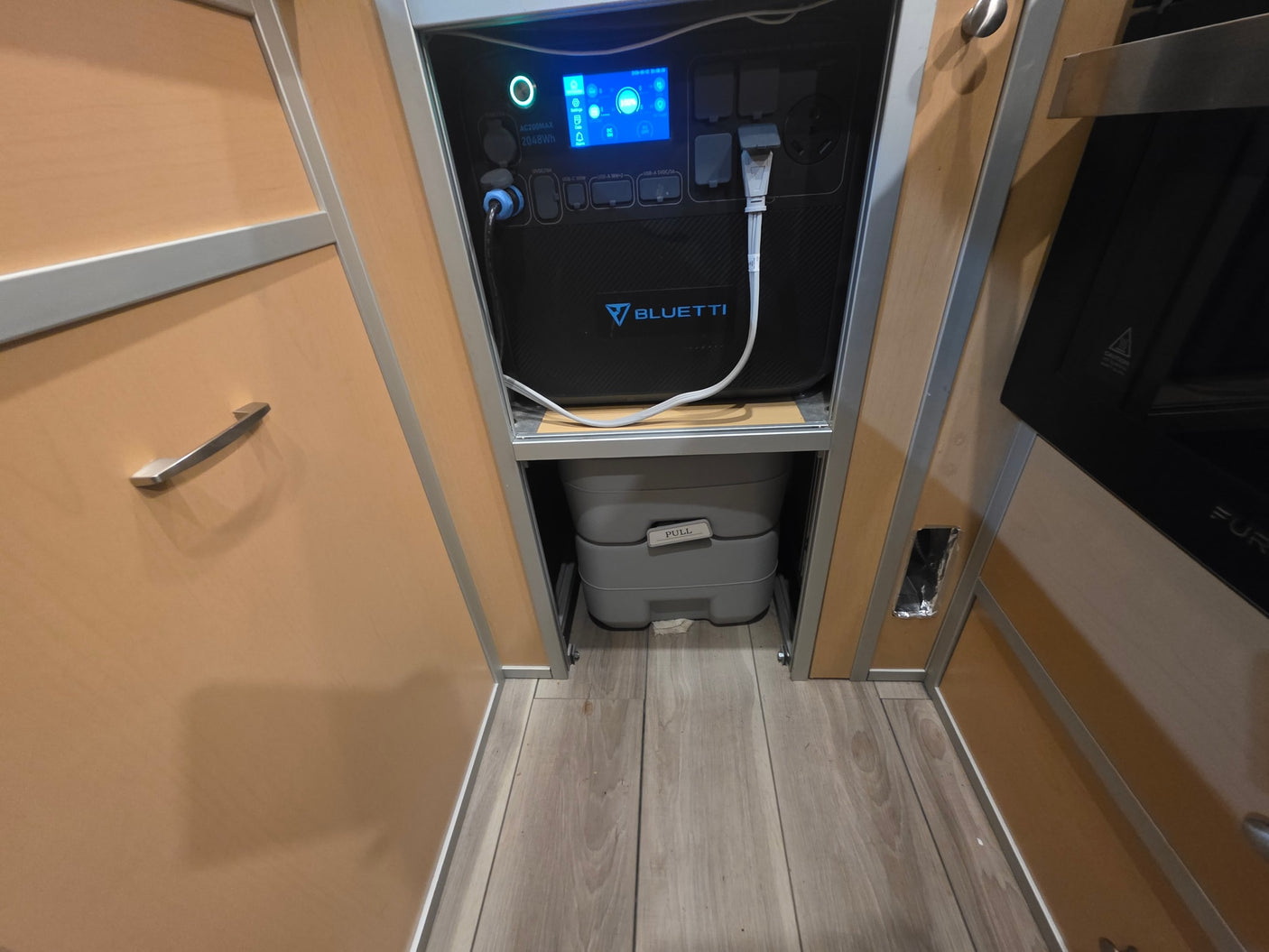 RV rental interior: A Bluetti AC200MAX power station (100% charged) powers devices above a portable toilet.