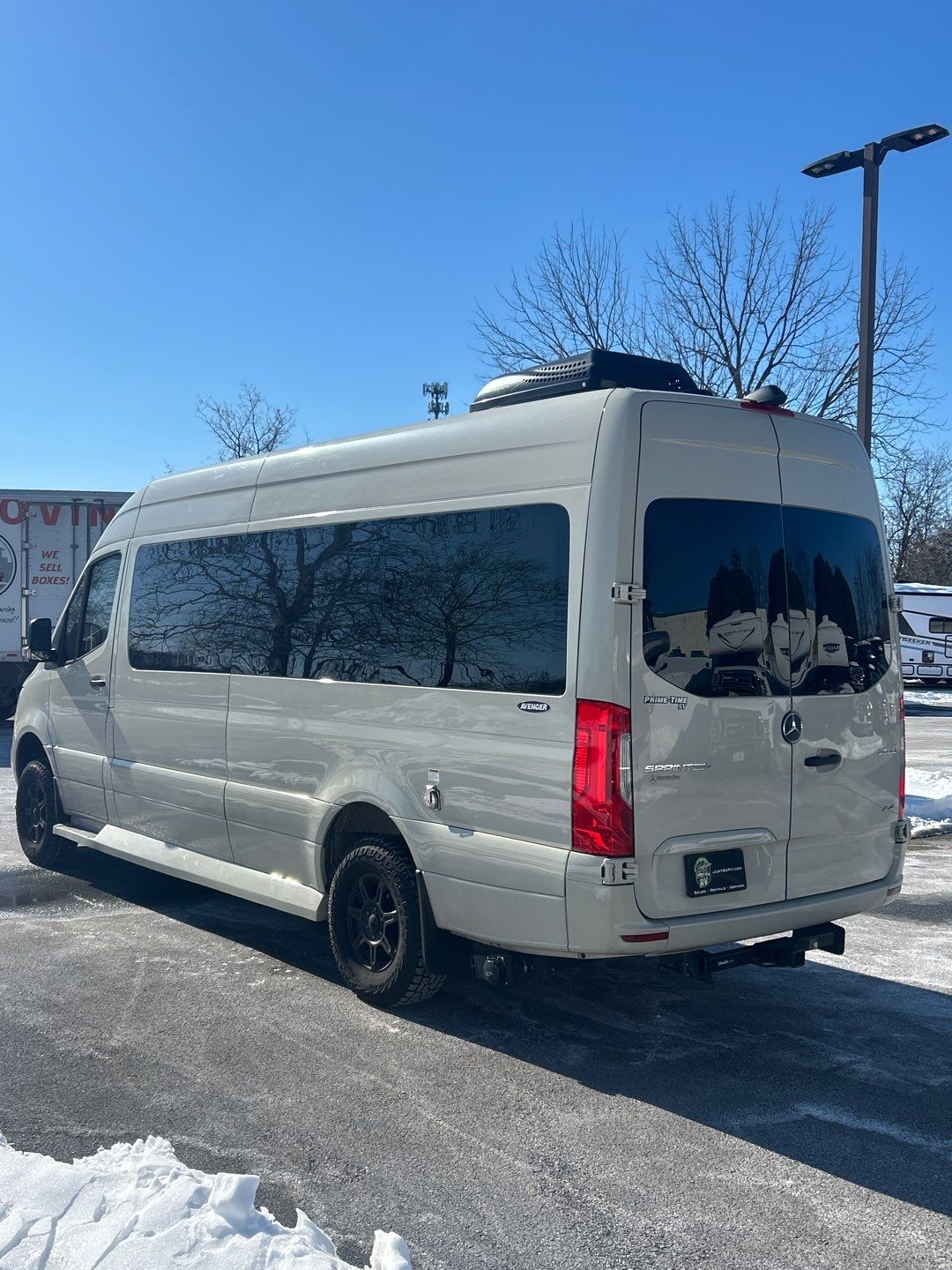 and a wide window view of other vehicles.|Compact RV rental lavatory with Dometic toilet & wall controls. Clean and functional interior for your travel needs.|Step inside this upscale RV rental: cream captain's chairs