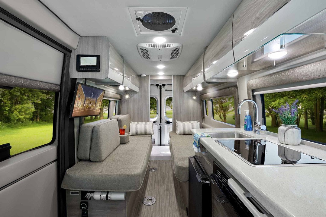 at a campsite with another RV in background. Perfect for road trips.|Explore this modern RV rental's inviting interior: sleek kitchen