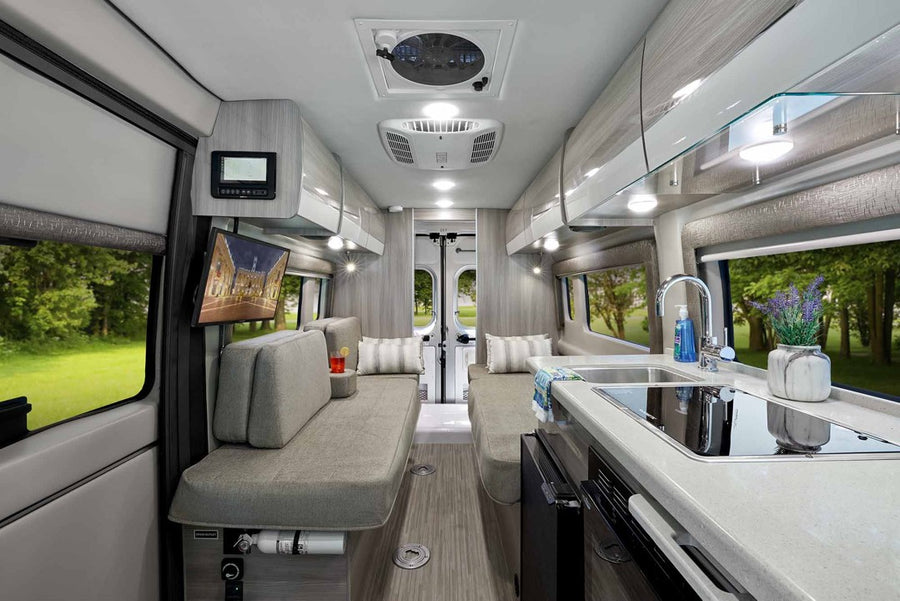 at a campsite with another RV in background. Perfect for road trips.|Explore this modern RV rental's inviting interior: sleek kitchen