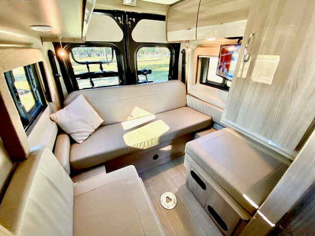 offering outdoor views.|This RV rental interior shows a cozy bed next to a kitchenette with a sink