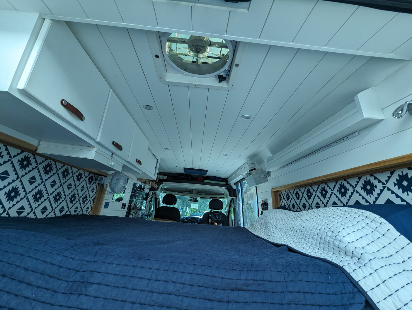 Experience van life in this rv rental. Features a spacious bed, overhead storage, & ceiling vent for comfort.