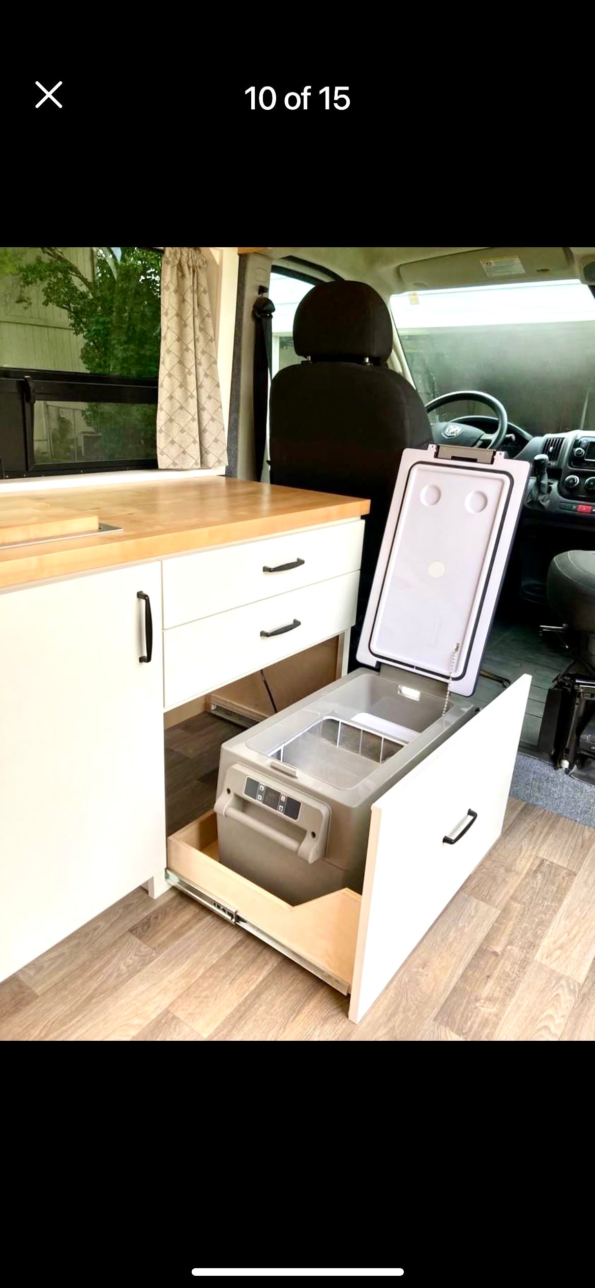 RV rental interior: organized kitchen with pull-out fridge/freezer, light wood counter, and white cabinets.