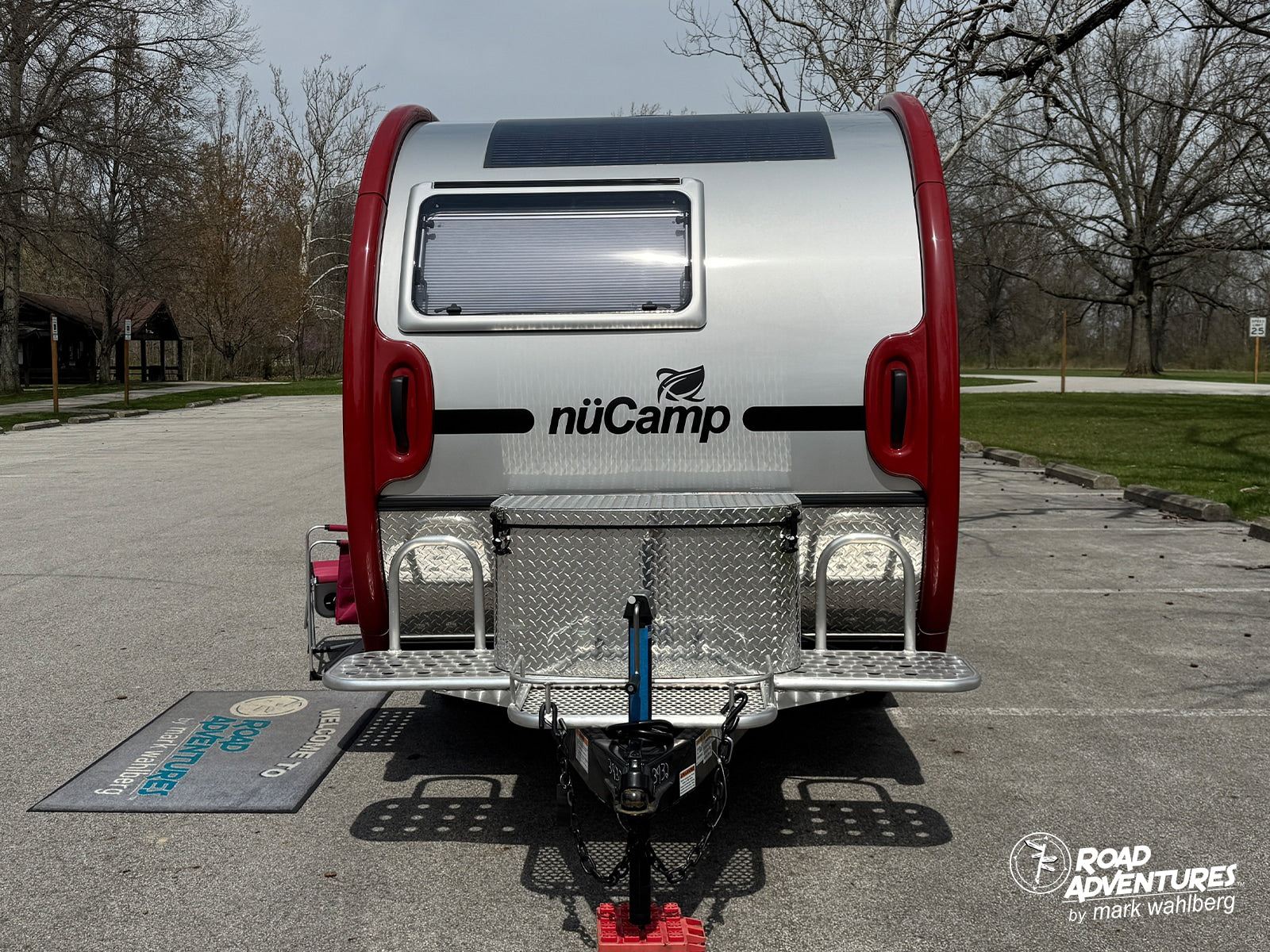 A shiny nuCamp teardrop travel trailer, an ideal **rv rental** for outdoor road trip adventures. Parked in a scenic lot.